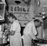 836804 Afbeelding van een kok en een kokkin in de keuken van het restauratierijtuig van de Hotelplan Expres van Den ...